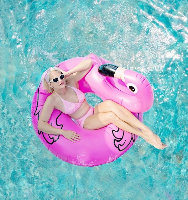 Woman lounging in a pink flamingo ring on a pool
