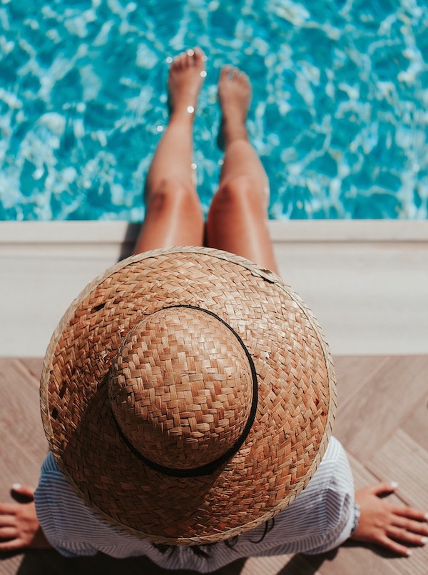 Woman wearing large sunhat with feet in pool